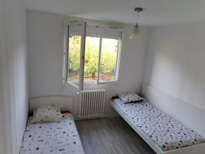 A small room with two single beds, a radiator, and a window with a view of greenery. - Entire house, private pool, and lush garden (1,500 m²) (Espiet)
