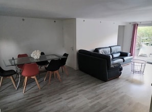 A modern living room with a glass dining table, black and red chairs, a black leather sofa, and a small round coffee table. - Entire house, private pool, and lush garden (1,500 m²) (Espiet)