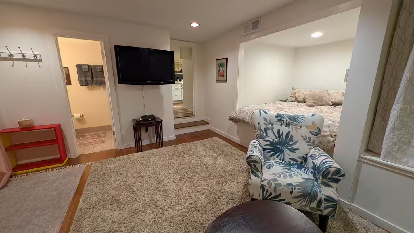 A bedroom with a bed, a TV, a sofa, and a small table.