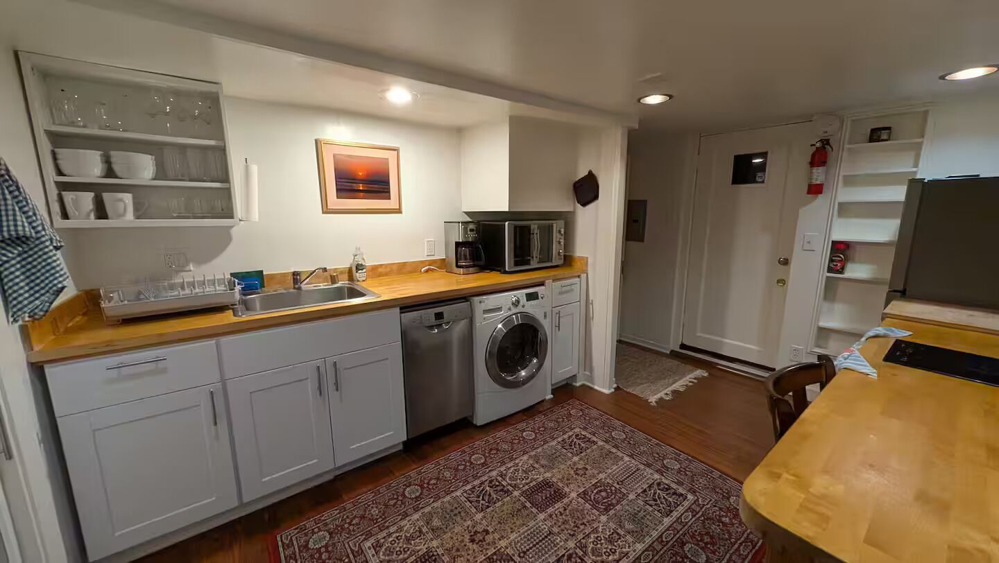 Een kleine keuken met een wasmachine, een magnetron en een spoelbak.