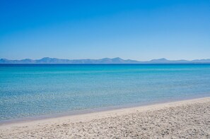 A beach with clear turquoise water and distant mountains under a clear blue sky. - House with Jacuzzi Can Grande Alcudia (Alcudia)