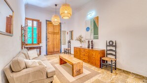 A living room with a sofa, wooden coffee table, and a dining area with a wooden cabinet and chairs. - House with Jacuzzi Can Grande Alcudia (Alcudia)