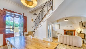 A spacious living area with a wooden dining table, a staircase, and a fireplace. - House with Jacuzzi Can Grande Alcudia (Alcudia)