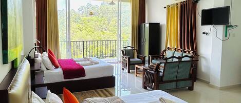 A hotel room with a large bed, a smaller bed, a desk with a chair, a television, and a balcony with curtains.