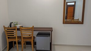 A small office space with a desk, two chairs, a coffee maker, and a refrigerator.