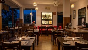 A cozy cafe with wooden furniture, a bar area with bottles, and a red sofa.