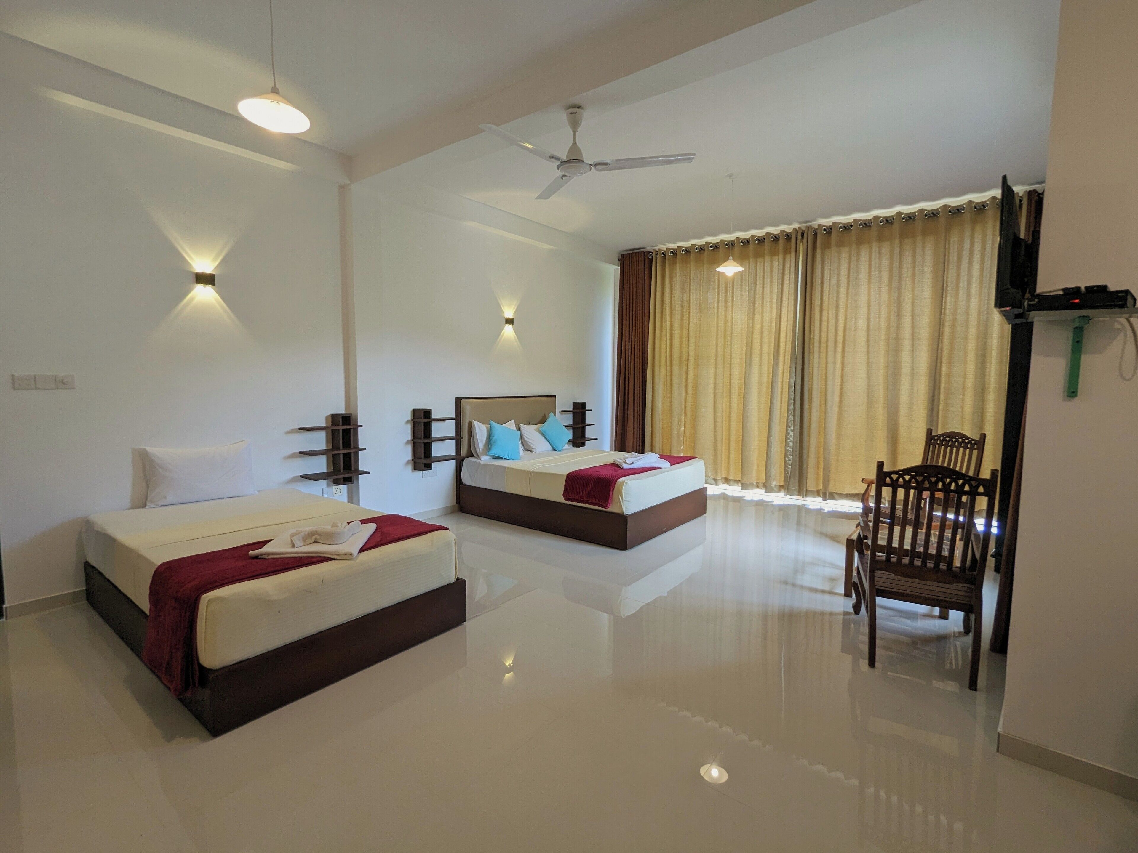 A hotel room with two beds, a ceiling fan, and a chair.