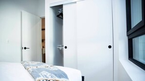 Ein Schlafzimmer mit Bett, Kleiderschrank und Fenster.