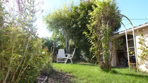 Ein Garten mit weißem Stuhl, einer Leiter und einem Gebäude mit Garage.