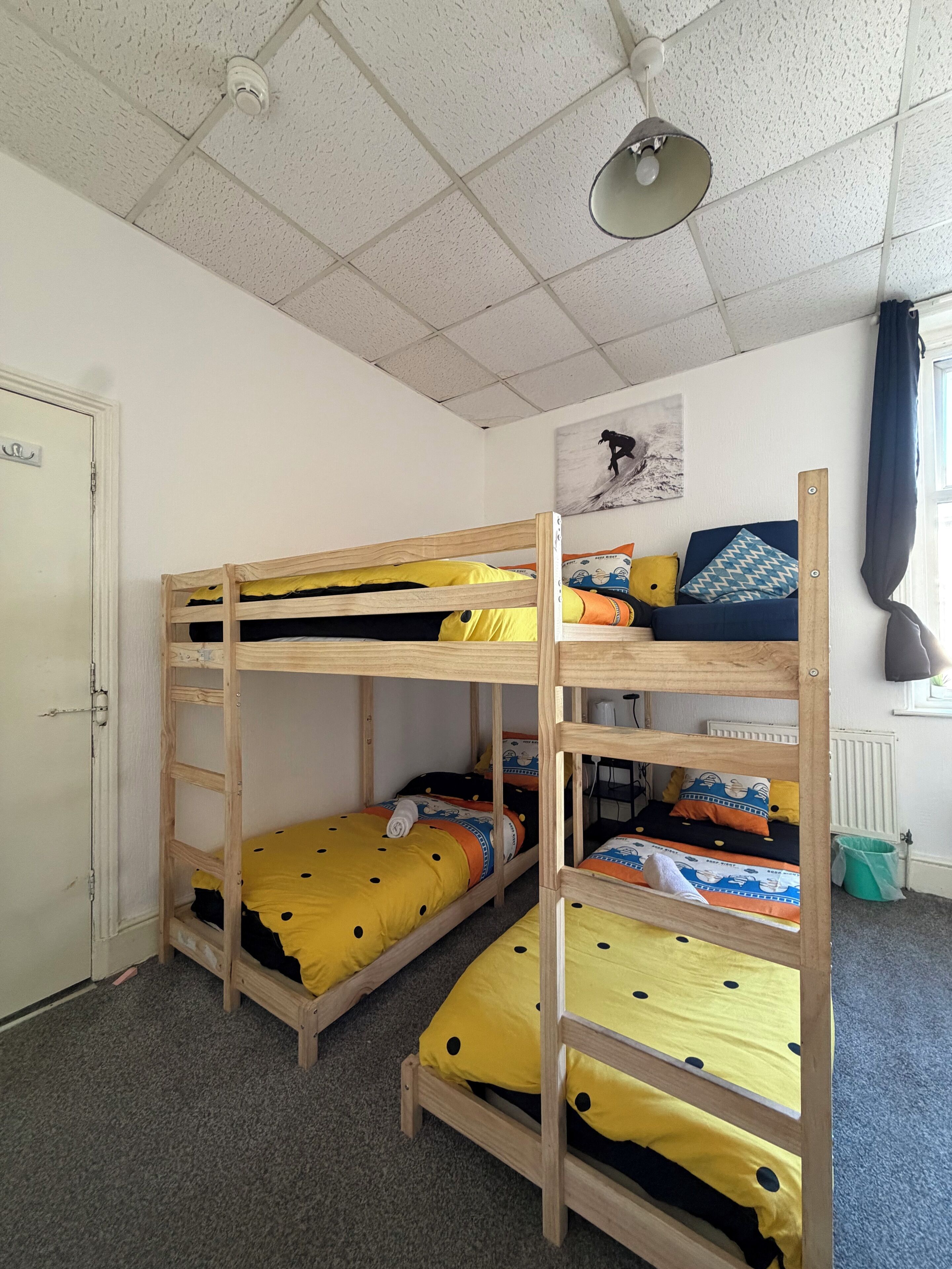A bunk bed room with a ceiling fan, a radiator, and a door.