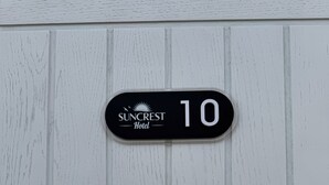 A black hotel sign with 'Suncrest Hotel' and the number '10' on a white wooden background. - Suncrest Hotel (Blackpool)