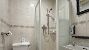 A bathroom with a toilet, a glass-enclosed shower, and a sink. - Suncrest Hotel (Blackpool)