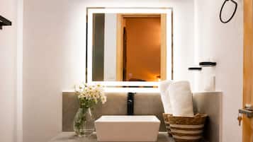 A bathroom vanity with a mirror, a vase of flowers, a towel, and a basket.