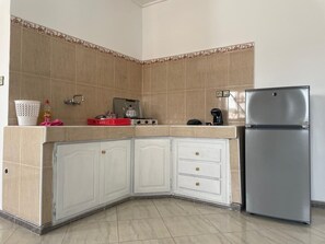 Una cocina con armarios blancos, un refrigerador de acero inoxidable y un salpicadero de azulejos.
