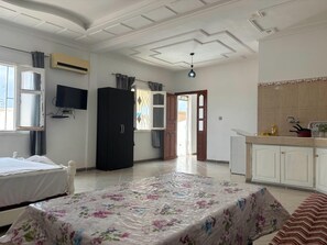 A bedroom with a bed, a wardrobe, a TV, and a kitchenette. - Darcom Rooftop Terrace - Studio with a large 70-square-meter terrace (Saïdia)