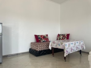 Una habitación pequeña con cama, una mesa y un refrigerador.
