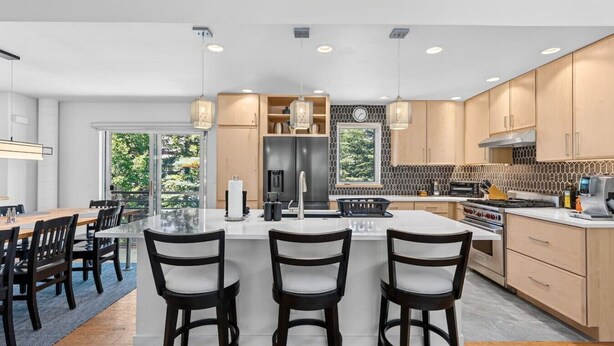 A modern kitchen with a central island, bar stools, and a dining area with a view. - Eagle Vail Mountain Retreat w/Fenced Yard (Avon)