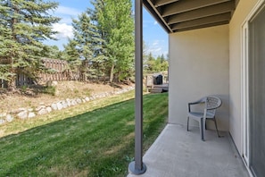 Eine Terrasse mit Betonboden, einem Metallpfosten und einem weißen Kunststoffstuhl.