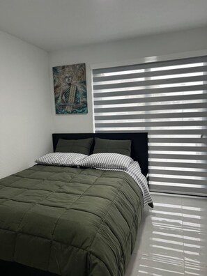 Une chambre à coucher avec un lit, un tableau et une fenêtre avec des stores.