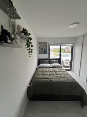 Une chambre à coucher avec un lit, une fenêtre donnant sur la rue et une statue de Bouddha accrochée au mur.