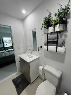 Ein modernes Badezimmer mit Waschbecken, Spiegel, Toilette und einem Handtuchhalter mit Handtüchern.