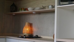 A kitchen with a gas stove, a hanging lamp, and a refrigerator.