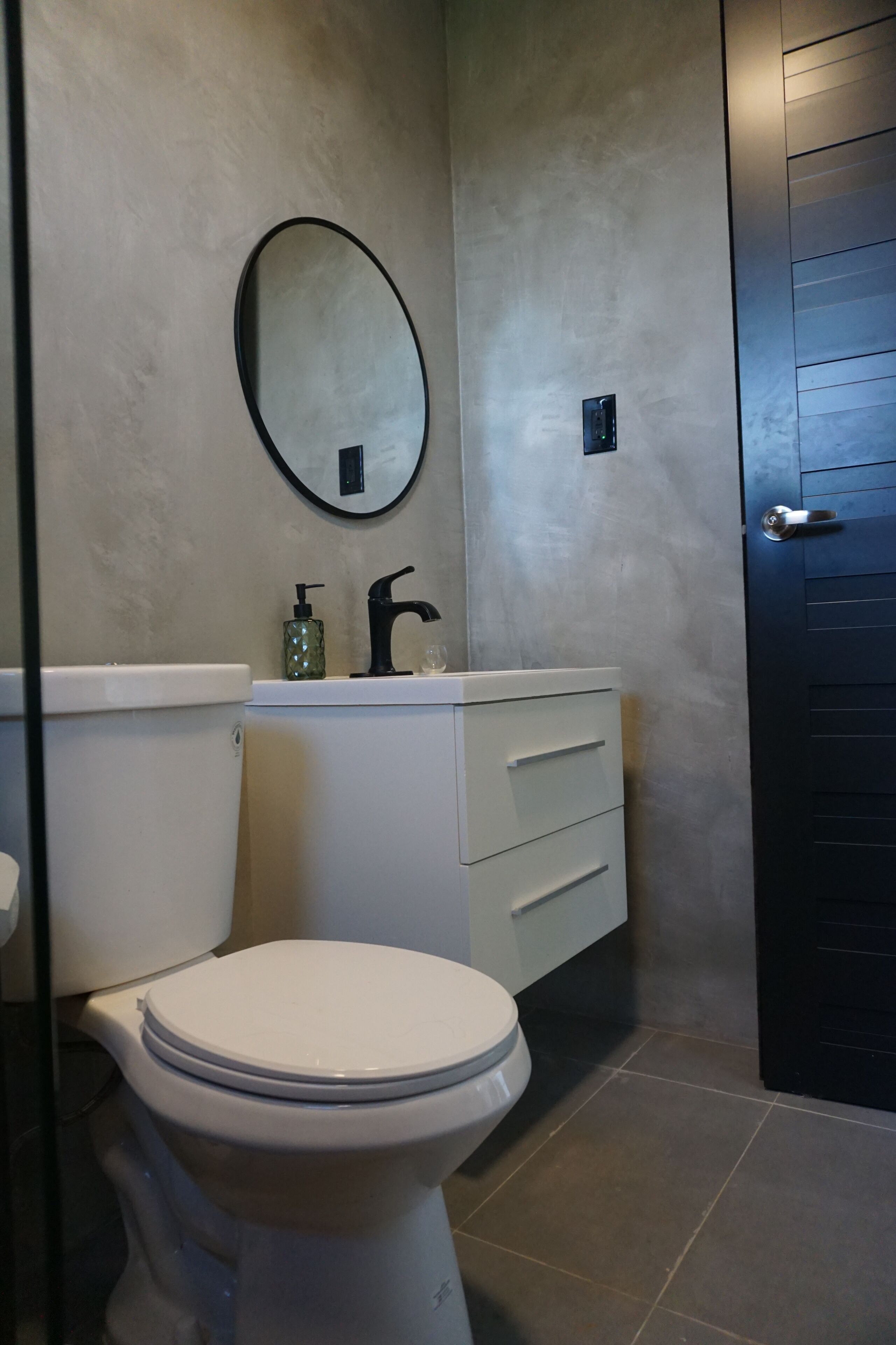 A bathroom with a toilet, a sink with a mirror, and a door.