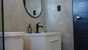 A bathroom with a toilet, a sink with a mirror, and a door.