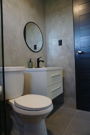 Une salle de bain avec des toilettes, un lavabo avec un miroir et une porte.