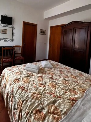 Ein Schlafzimmer mit einem Bett, zwei Türen, einem Sessel und einem Fernseher an der Wand.
