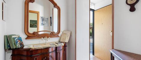 A bathroom with a wooden vanity, a large mirror, and a wall-mounted clock.