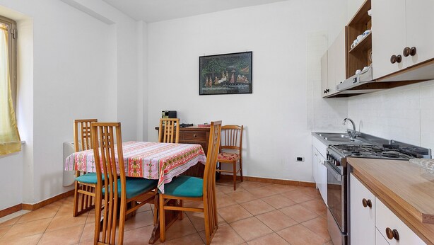 A compact kitchen with a dining area, a stove, and a painting on the wall.