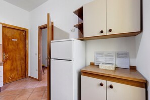 Una cocina compacta con un refrigerador blanco, armarios de madera y piso de baldosas.