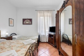 Quarto com cama, mesa de cabeceira com abajur, televisão e armário.