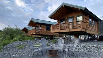 A log cabin with a balcony, outdoor seating, and a fire pit.