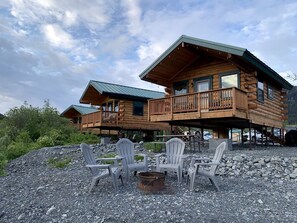 Une cabane en rondins dotée d’un balcon, d’un espace salon extérieur et d’un foyer.