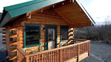 A log cabin with a porch, a door, and a window.