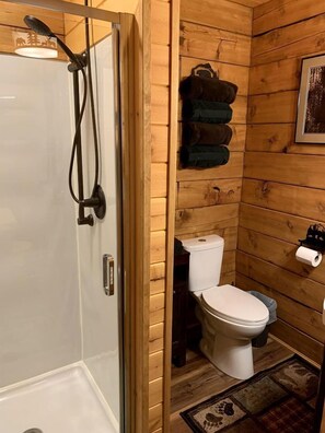 Een betegelde badkamer met douche, toilet en handdoekrek.