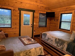 Een chalet met twee bedden, een houten deur en ramen met zonwering.