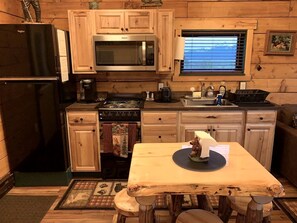 Une cuisine de taille réduite, dotée de meubles en bois, d’un four à micro-ondes, d’une cuisinière et d’un évier.