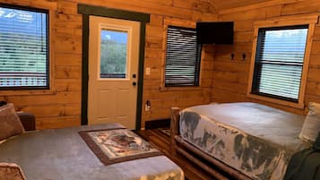 Een chalet met twee bedden, een houten deur en ramen met zonwering.