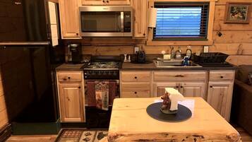 Une cuisine de taille réduite, dotée de meubles en bois, d’un four à micro-ondes, d’une cuisinière et d’un évier.