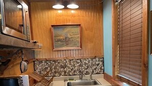 Une cuisine de taille réduite, avec des meubles de rangement en bois, un évier et une cuisinière.