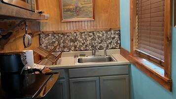 A compact kitchen with wooden cabinets, a sink, and a stove.