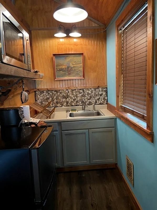 A compact kitchen with wooden cabinets, a sink, and a stove.