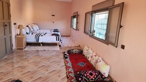 Un dormitorio con cama, mesita de noche, lámpara, ventana con rejas y alfombra estampada.