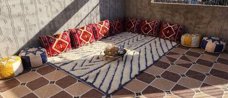 A room with a patterned floor, a rug with a geometric design, and a window with a view of the outside.