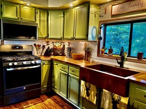 A kitchen with green cabinets, a stove, and a window with plants.