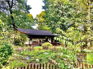 A house with a porch, surrounded by a garden and a wooden fence.