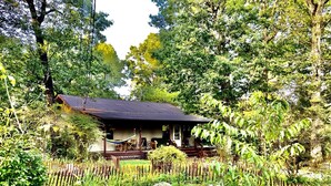 Ein Haus mit Veranda, umgeben von einem Garten und einem Holzzaun.